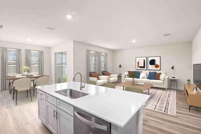 kitchen featuring a sink, visible vents, light countertops, light wood-type flooring, and dishwasher