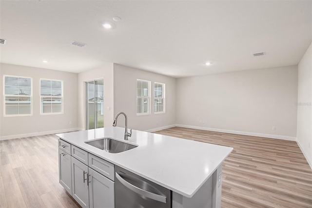 kitchen with a sink, open floor plan, light countertops, stainless steel dishwasher, and light wood finished floors