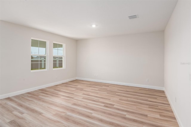 unfurnished room featuring visible vents, light wood-style flooring, and baseboards