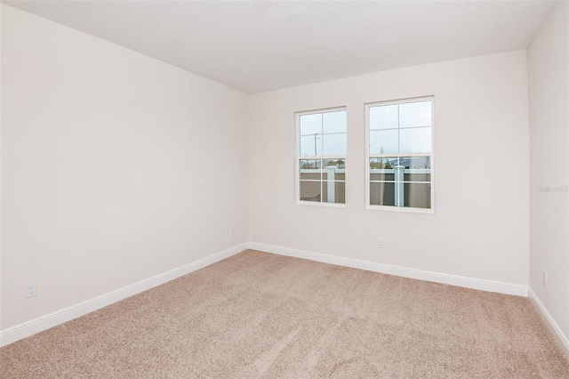 carpeted spare room featuring baseboards