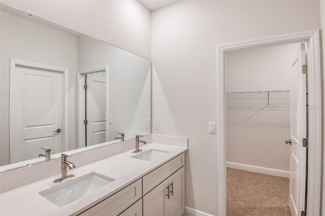 full bathroom featuring a sink, a spacious closet, baseboards, and double vanity