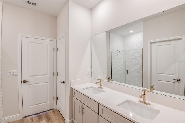 bathroom with visible vents, a sink, a shower stall, and wood finished floors