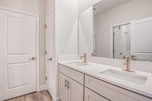 bathroom featuring double vanity, visible vents, a sink, and wood finished floors