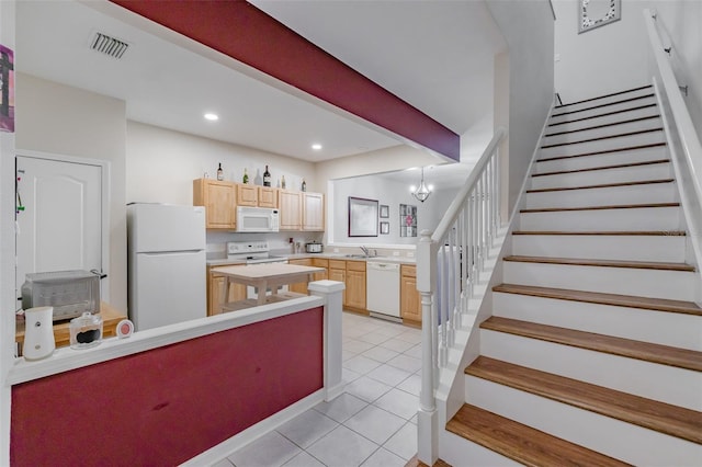 kitchen featuring white appliances, sink, light tile patterned floors, light brown cabinetry, and a chandelier