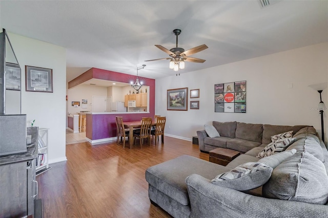 living room with hardwood / wood-style flooring and ceiling fan with notable chandelier