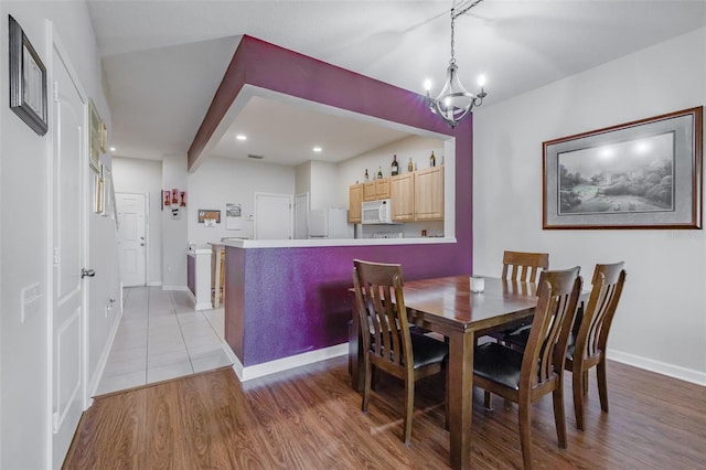 dining room with light hardwood / wood-style floors and an inviting chandelier