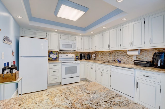 kitchen featuring white appliances, white cabinetry, a raised ceiling, and sink