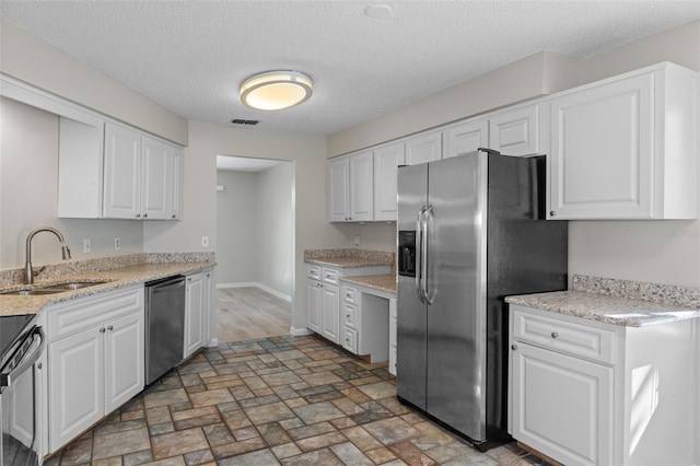 kitchen with white cabinets, sink, appliances with stainless steel finishes, and a textured ceiling