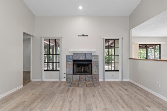 unfurnished living room with a tile fireplace and light hardwood / wood-style flooring