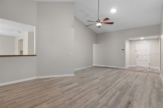 unfurnished living room with ceiling fan, light hardwood / wood-style floors, a textured ceiling, and high vaulted ceiling