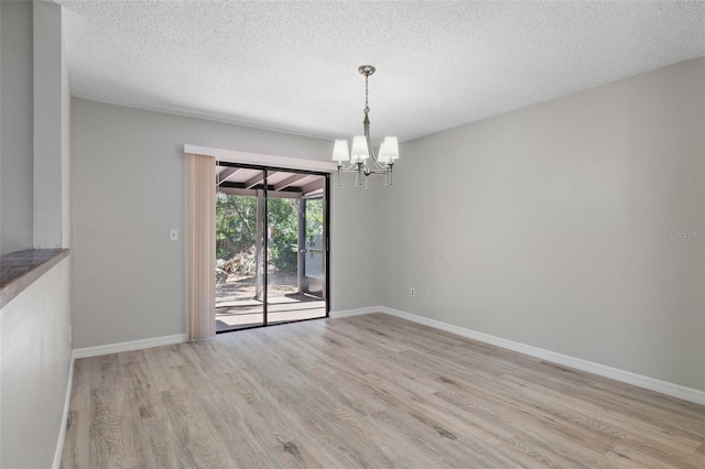 unfurnished dining area with light hardwood / wood-style flooring, a textured ceiling, and an inviting chandelier