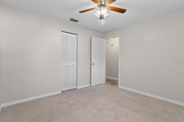 unfurnished bedroom featuring ceiling fan, light colored carpet, a textured ceiling, and a closet