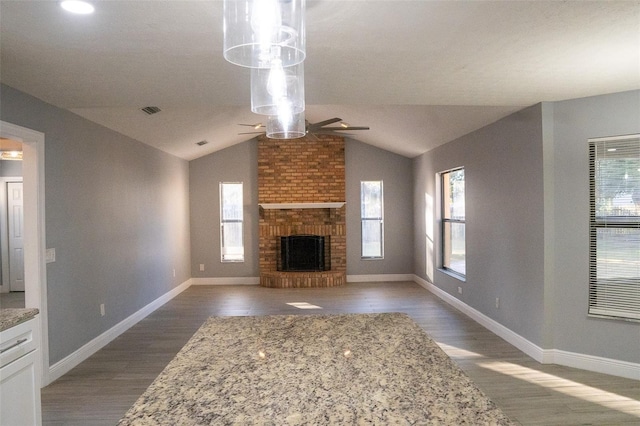 unfurnished living room with dark hardwood / wood-style flooring, lofted ceiling, a fireplace, and a wealth of natural light