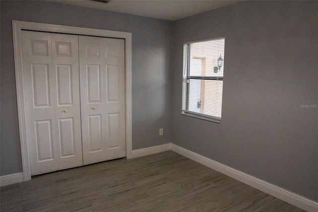 unfurnished bedroom featuring wood-type flooring and a closet