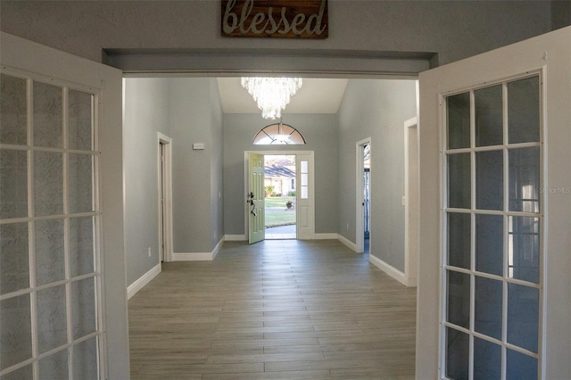 foyer entrance featuring a chandelier, hardwood / wood-style floors, and vaulted ceiling