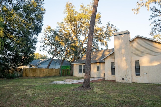 rear view of house with a lawn and an outdoor fire pit