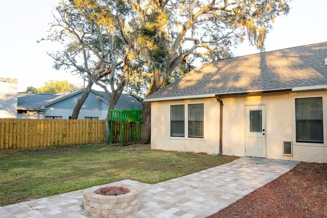 rear view of house with a yard, an outdoor fire pit, and a patio area