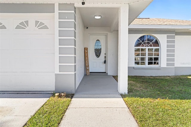 entrance to property with a garage and a lawn