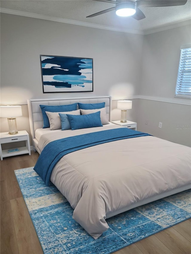 bedroom with a textured ceiling, hardwood / wood-style flooring, ceiling fan, and ornamental molding