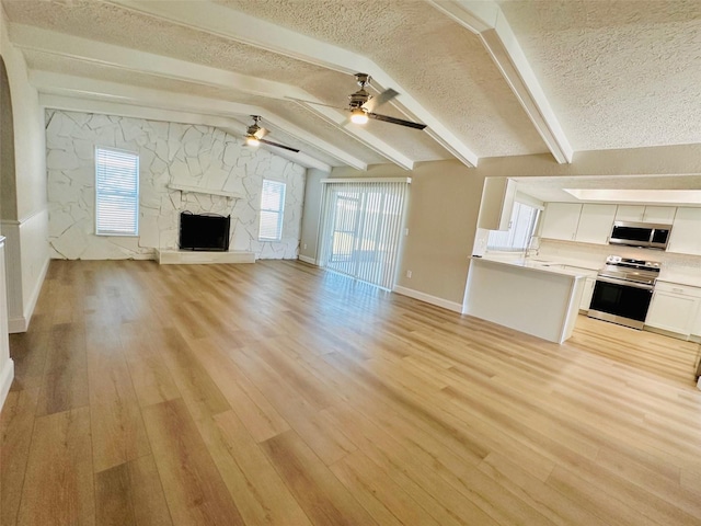 unfurnished living room featuring a fireplace, light hardwood / wood-style floors, a textured ceiling, and a wealth of natural light