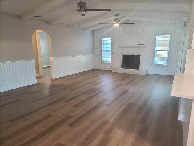 unfurnished living room with hardwood / wood-style floors, vaulted ceiling with beams, ceiling fan, and a fireplace