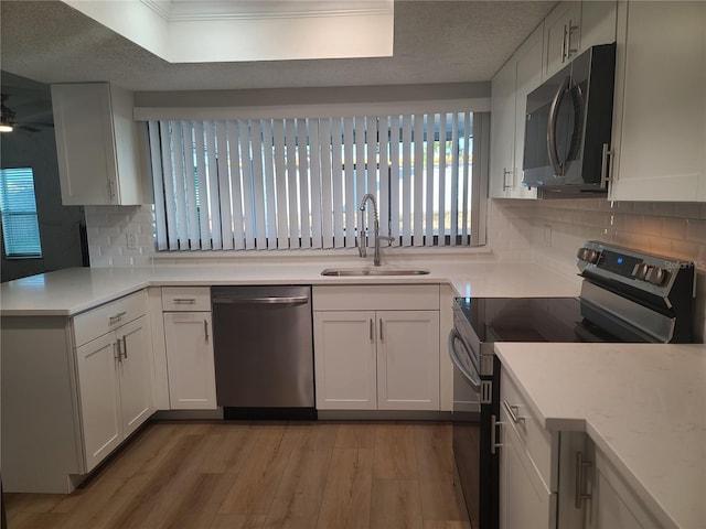 kitchen with white cabinetry, sink, appliances with stainless steel finishes, and light hardwood / wood-style flooring