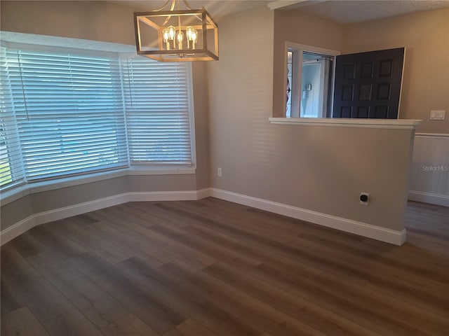 unfurnished room with a textured ceiling, dark hardwood / wood-style floors, and a notable chandelier