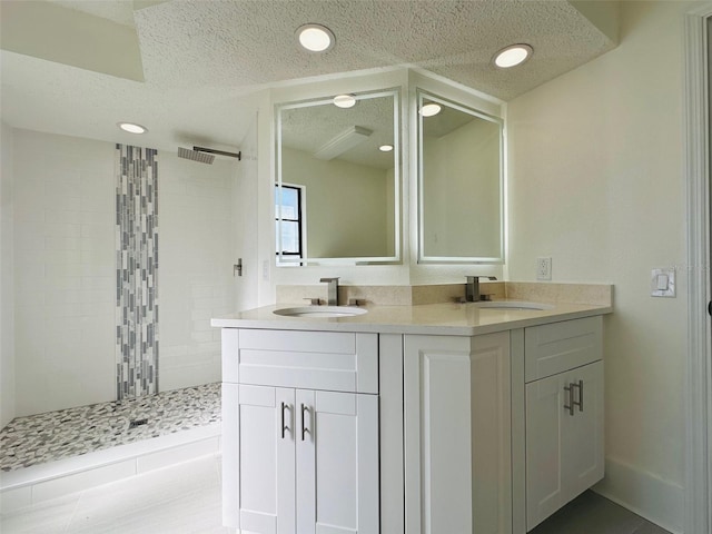 bathroom featuring tile patterned floors, vanity, a tile shower, and a textured ceiling