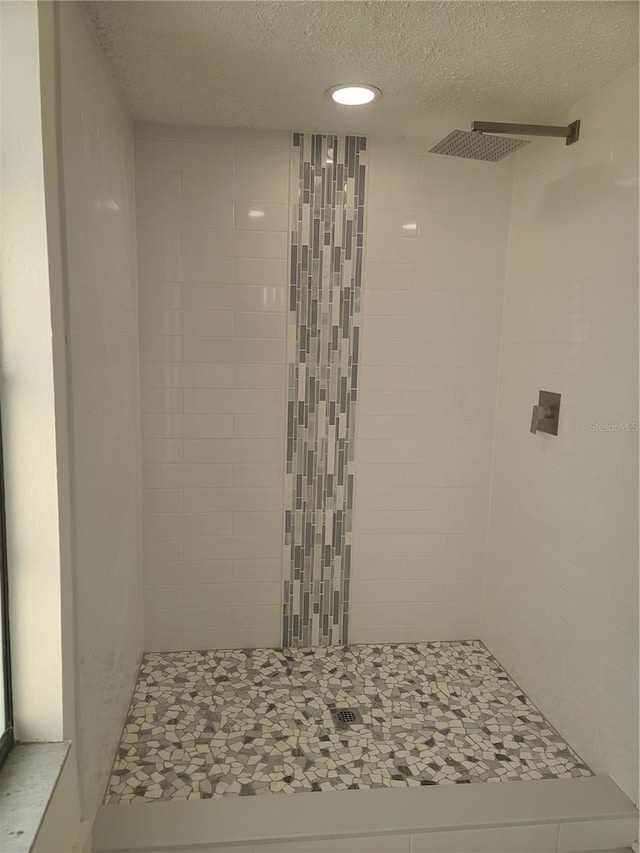 bathroom with a tile shower and a textured ceiling