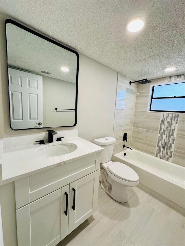 full bathroom featuring vanity, a textured ceiling, tiled shower / bath combo, and toilet