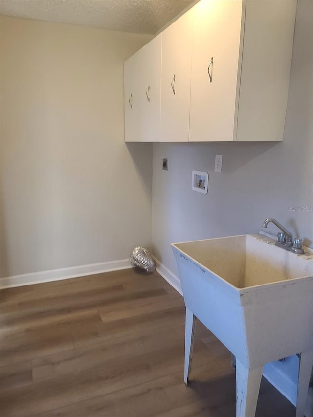 laundry room featuring cabinets, hookup for a washing machine, a textured ceiling, electric dryer hookup, and hardwood / wood-style floors