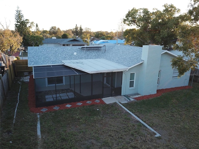 rear view of property featuring a sunroom and a yard