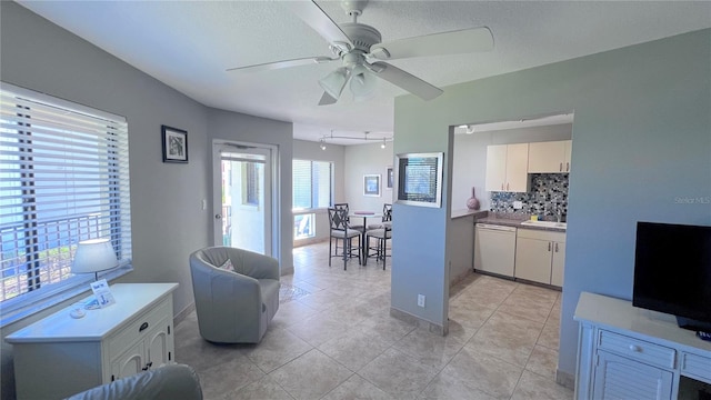 tiled living room with a textured ceiling, ceiling fan, and sink