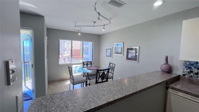 dining space with a textured ceiling and rail lighting