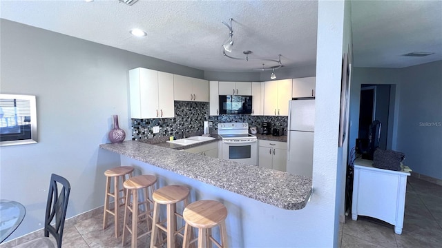 1515 Pinellas Bayway S Unit 35, Tierra Verde, FL 33715 - kitchen with white appliances, tasteful backsplash, a breakfast bar area, a sink, and a peninsula