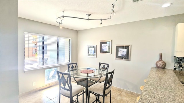 tiled dining space featuring rail lighting and a textured ceiling