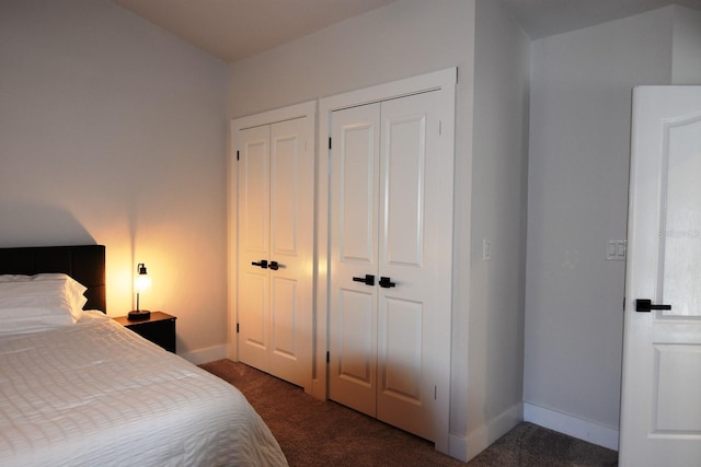 bedroom featuring two closets and dark colored carpet