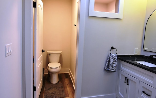 bathroom featuring wood-type flooring, toilet, and vanity