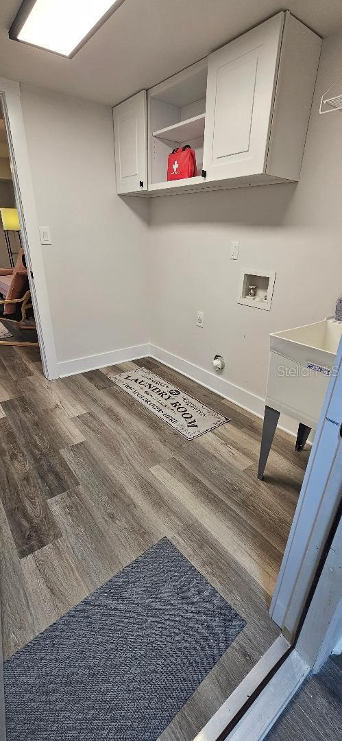 washroom featuring dark wood-type flooring, washer hookup, and cabinets