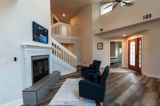 living room with ceiling fan, plenty of natural light, dark hardwood / wood-style floors, and a towering ceiling