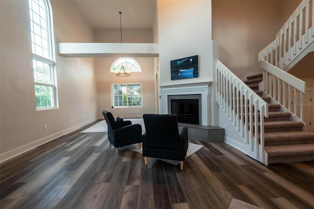 living room featuring a chandelier, a towering ceiling, and dark hardwood / wood-style floors