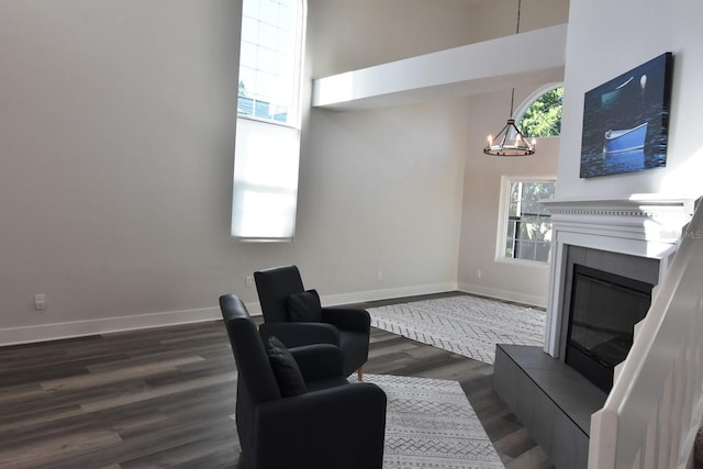 living room featuring a towering ceiling, dark hardwood / wood-style floors, and a chandelier