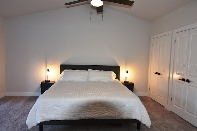 bedroom featuring vaulted ceiling, ceiling fan, two closets, and dark colored carpet