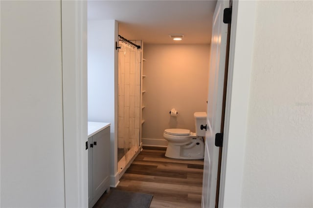 bathroom featuring toilet, wood-type flooring, walk in shower, and vanity