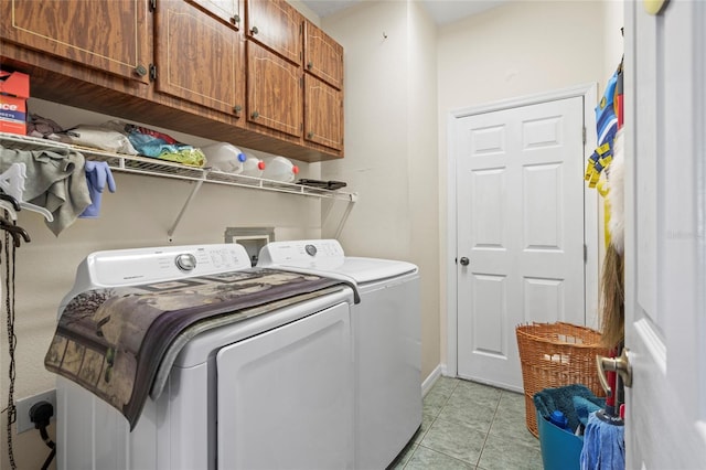 clothes washing area with cabinets, washing machine and dryer, and light tile patterned flooring