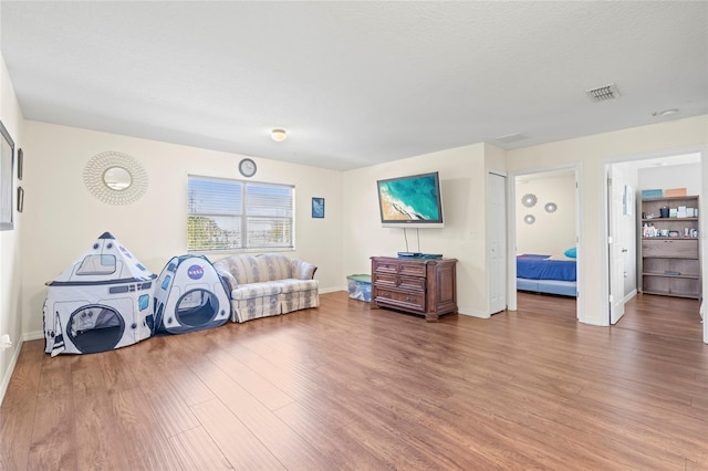 sitting room featuring baseboards, a textured ceiling, visible vents, and wood finished floors