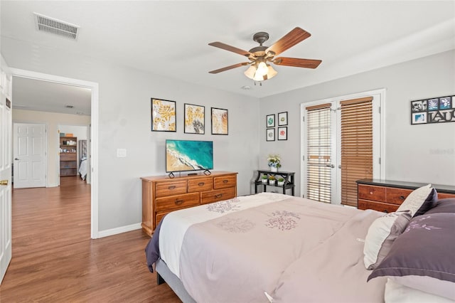 bedroom featuring a ceiling fan, baseboards, visible vents, and wood finished floors