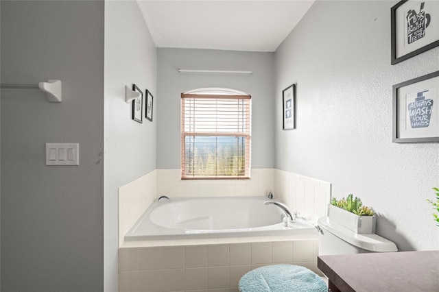 bathroom with vanity, a relaxing tiled tub, and toilet