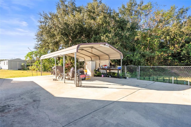 exterior space featuring an outdoor structure, fence, driveway, a detached carport, and a storage unit