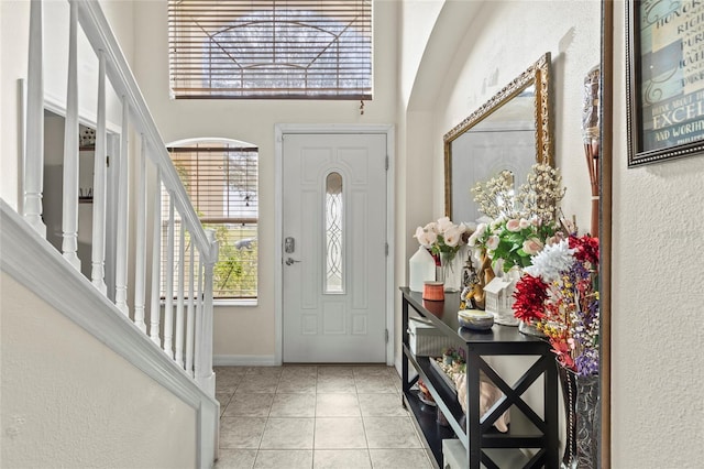 foyer entrance featuring stairs, a high ceiling, and light tile patterned flooring